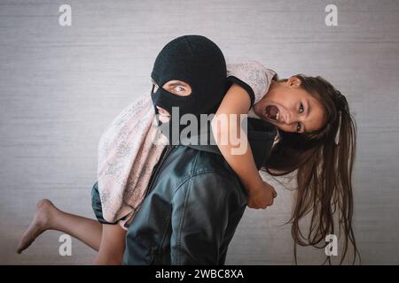 Terrorist and scared little hostage on white background. The concept of kidnapping. The kidnapper stole a teenage girl's child Stock Photo