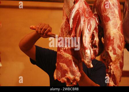 Butcher's hands cutting meat with knife in shop Stock Photo