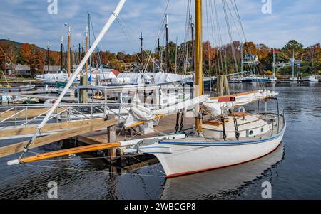 Small Sailboat at a New England Dock:  A boat with furled sails sits quietly by a wooden pier on an October day in Camden, Maine. Stock Photo
