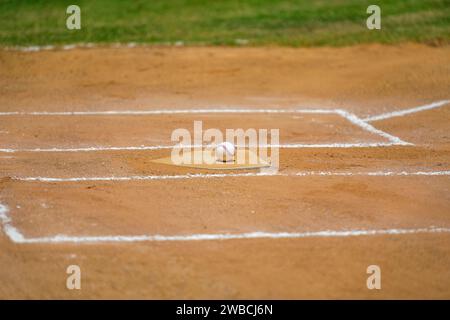 Baseball game, baseball ball sitting on the home plate, base, during the baseball game. Stock Photo