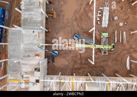 Drone photography of constructions site of large commercial building with construction machinery and construction workers during autumn sunny morning Stock Photo