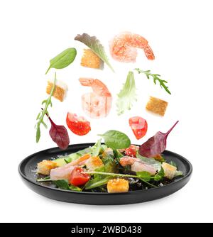 Ingredients falling into plate with tasty salad on white background Stock Photo