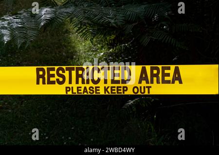 A bright yellow, 'Restricted Area, Please Keep Out' tape is stretched across an entrance Stock Photo