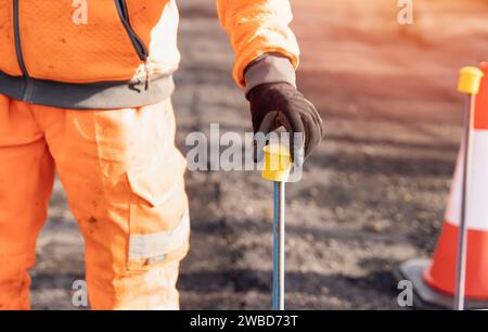Builder placing yellow plastic safety protecting caps on top of road setting out steel pins on a road improvement project Stock Photo