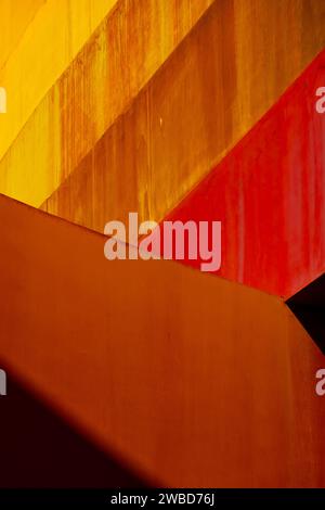 Vivid abstract architectural detail with intersecting red and orange planes creating a dynamic play of light and shadow Stock Photo