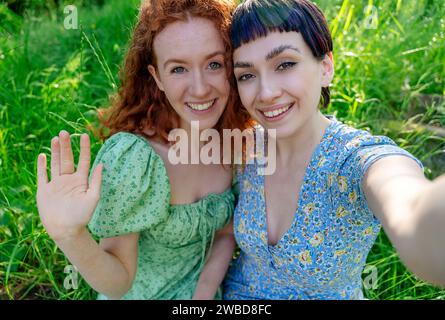 two friend, girlfriend and women using a mobile phone, camera and taking selfie in public park. Romantic concept Stock Photo