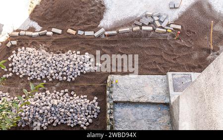 Resurfacing the road surface, manual laying of porphyry cubes on the road. Paving realized with red Trentino Porphyry cubes, Trentino Alto Adige,Italy Stock Photo