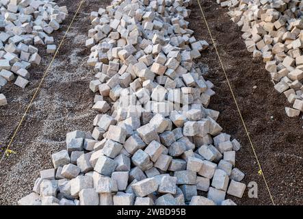 Resurfacing the road surface, manual laying of porphyry cubes on the road. Paving realized with red Trentino Porphyry cubes, Trentino Alto Adige,Italy Stock Photo