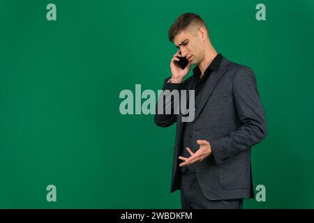young bearded businessman or boss is seriously talking on the phone. isolated on green. High quality photo Stock Photo