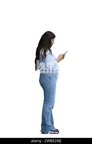 A girl in a blue shirt, on a white background, full-length, with a phone in her hands, in profile Stock Photo