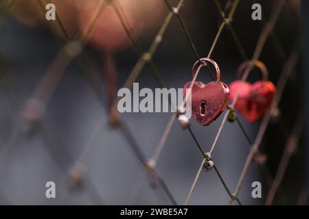 A red old ceremony padlock closed on a bridge. People hang those traditional in celebration of  happines, love, friendship, marriage and engagement. Stock Photo