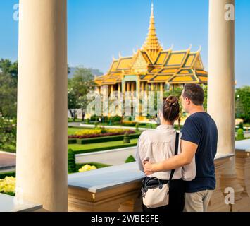 Tourist couple in Phnom Penh, Cambodia. Tourism in Royal Palace. Travel in Asia.  Woman and man visiting landmark. City vacation. Gold building. Stock Photo