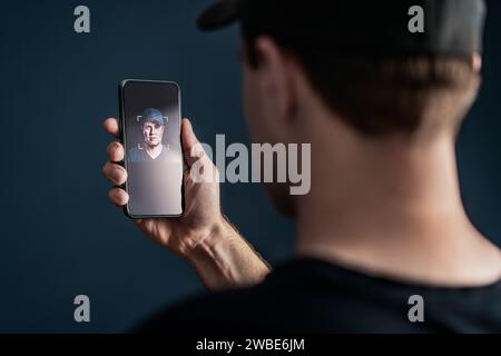 Face recognition with facial scan in phone. Identification and verification to unlock smartphone. Deep fake technology. Man using cellphone. Stock Photo