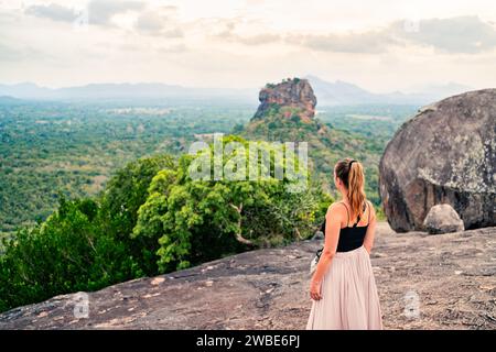 Woman in Sigiriya, Sri Lanka. Travel in beautiful nature. Mountain and forest landscape. Happy girl. Tourist looking at Lion's Rock from Pidurangala h Stock Photo