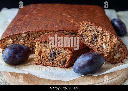 Traditional delicious plum cake with nuts and cut into pieces on an wooden board close-up, selective focus. Stock Photo