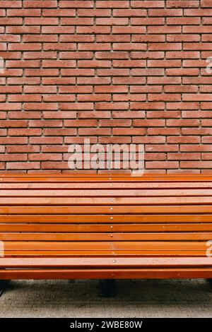 Vertical banner with bench on red-brown vintage brick wall texture background, concept for advertising on brick wall background Stock Photo