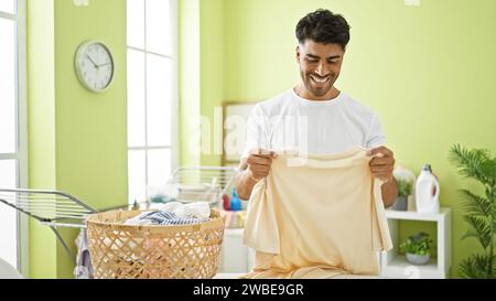 Smiling young man folding laundry in a bright home interior Stock Photo