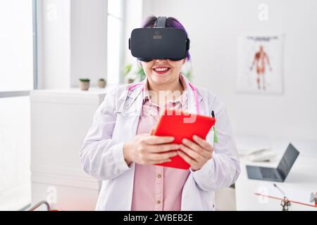 Young beautiful plus size woman doctor using virtual reality glasses at clinic Stock Photo