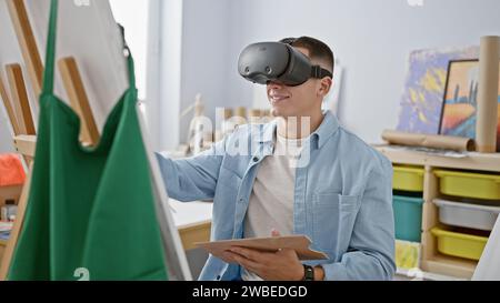 A young man engages with virtual reality in a creative indoor studio while holding a tablet. Stock Photo