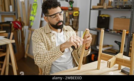 A bearded craftsman measures wooden pieces accurately in a well-equipped carpentry studio, showcasing skill and precision. Stock Photo