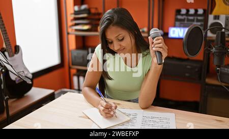 Young latin woman musician smiling confident composing song at music studio Stock Photo