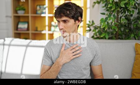 Young hispanic man with hands on chest at home Stock Photo