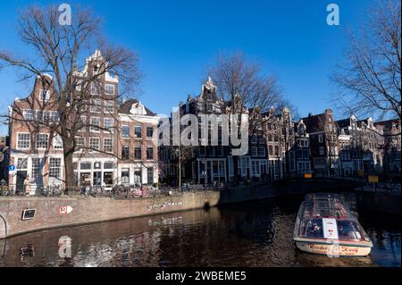 Amsterdam The Netherlands 10th January 2024 Winter scene in Amsterdam under crisp azure blue skies a tourist sightseeing rondvaart boat passes from the Herengracht into the Brouwersgracht canal. grachten, toerisme, Stock Photo
