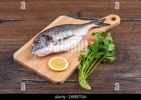 Fresh dorado fish with lemon and cilantro on a wooden cutting board. Home cooking. Stock Photo