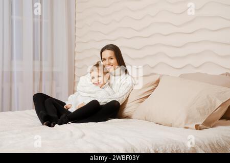 Happy young mother embracing her five years old daughter while being in bed Stock Photo