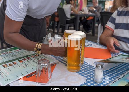 Waiter serves three beers at a table, Genoa, Italy Stock Photo