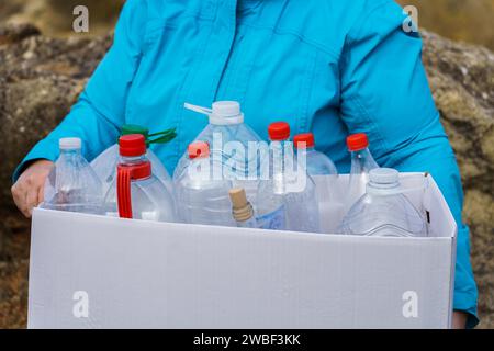 Woman holding a white cardboard box full of empty plastic bottles for recycling, environmental protection and ecology concept Stock Photo