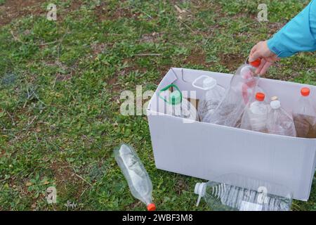 Woman collecting empty plastic bottles in the field to recycle, concept of ecology and respect for the environment Stock Photo