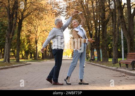 Affectionate senior couple dancing together in autumn park Stock Photo