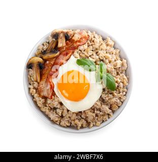 Bowl with tasty oatmeal, fried bacon, mushroom and squash on table ...