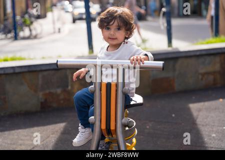 Portrait of a cute girl in an urban playground sitting on a bike figure Stock Photo