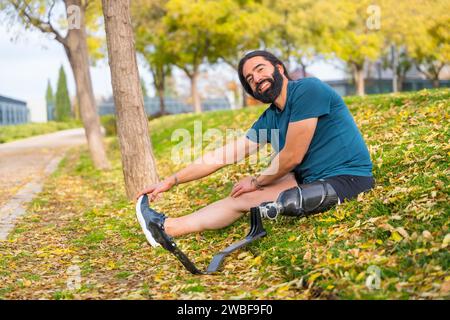 Happy man with a artificial leg stretching after exercising in an urban park Stock Photo
