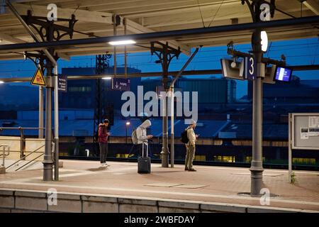 People on the platform early in the morning in front of the stainless steel plant, main railway station, Witten, North Rhine-Westphalia, Germany Stock Photo