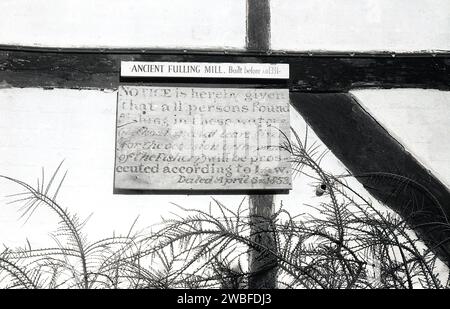 1960s, historical, written on old thatched wooden frame building at Alresford, over the River Alre are the words; Fulling Mill. Built before AD1331..... Below this a notice saying.. No fishing in river allowed....dated 1853. Stock Photo