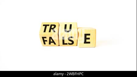 False or true symbol. Turned wooden cubes and changed the word false to true or vice versa. Beautiful white table, white background, copy space. Busin Stock Photo