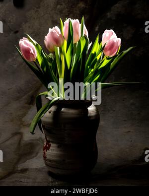 Fresh bouquet of pink tulips in an old clay jug Stock Photo