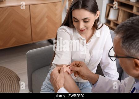 Young woman receiving vaccine from doctor at home Stock Photo