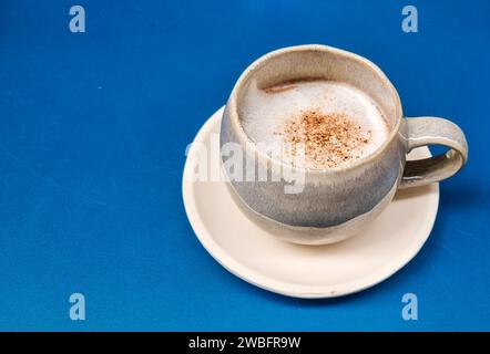 A white ceramic cup with a light yellow liquid and a white powder on top of it, isolated on a white background Stock Photo