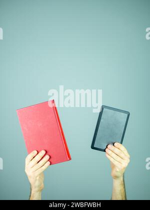 Two hands holding a red cover paper book and an electronic book Stock Photo