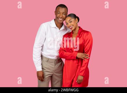 Happy black couple posing in elegant attire on pink background Stock Photo