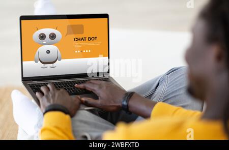 Over shoulder view african american man using chatbot on computer Stock Photo
