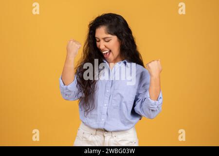 Exuberant young woman with long curly hair, wearing a blue blouse Stock Photo