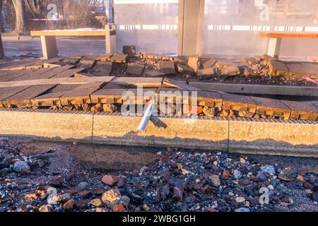 In den frühen Morgenstunden des heutigen Tages ereignete sich an der Haltestelle Hauptbahnhof-Westseite in Leipzig ein Wasserrohrbruch, der vermutlich auf kältebedingte Ursachen zurückzuführen ist. Eine Trinkwasserleitung brach direkt unter dem Wartehäuschen, wodurch das Gehwegpflaster aufbrach und das Wartehäuschen schwer beschädigt wurde. Bei eisigen Temperaturen von -11Â Celsius floss das Wasser etwa eine Stunde lang die Kurt-Schumacher-Straße hinunter, bis die Leipziger Stadtwerke erfolgreich die Leitung schließen konnten. Die Baustelle des Hotel Astoria wurde ebenfalls in Mitleidenschaft Stock Photo