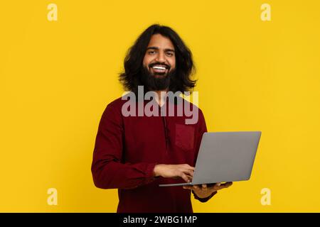 Cheerful young indian guy student using laptop Stock Photo