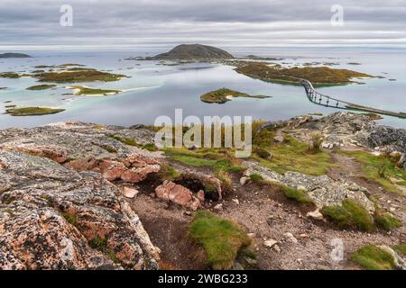 the bridge of Sommarøy, it curves majestically and crosses the Atlantic on the coast of Troms, Norway. autumnal colored plants on the shore of ocean Stock Photo