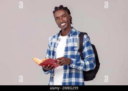 Education concept. Handsome african american guy with backpack and book Stock Photo